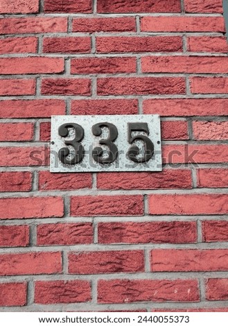 Number plate. Number 335 against a red brick wall background. Concept from a room and a wall. High resolution 150 megapixels Royalty-Free Stock Photo #2440055373