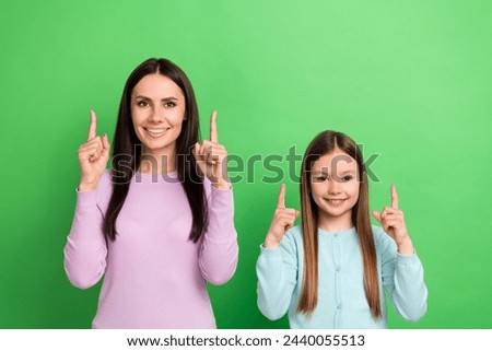 Portrait of two people mother daughter indicate fingers up empty space isolated on bright green color background