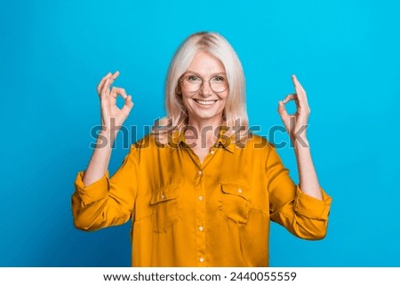 Photo portrait of pretty pensioner female showing okey symbol wear trendy orange smart casual outfit isolated on blue color background