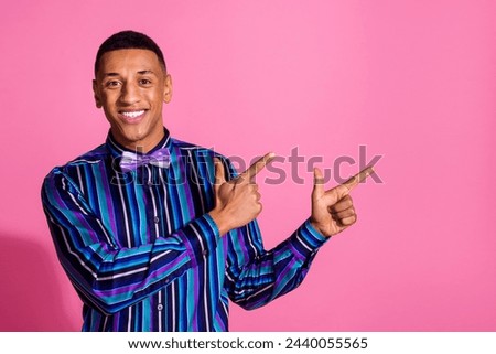 Photo of cheerful positive guy dressed striped shirt showing two fingers empty space isolated pink color background
