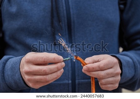 Close up of man hand lighting up a firecrackers with wick. Man holding a burning petard in his hand. Royalty-Free Stock Photo #2440057683
