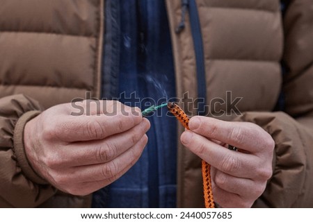 Close up of man hand lighting up a firecrackers with wick. Man holding a burning petard in his hand. Royalty-Free Stock Photo #2440057685