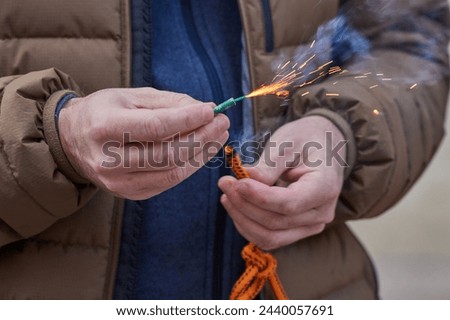 Close up of man hand lighting up a firecrackers with wick. Man holding a burning petard in his hand. Royalty-Free Stock Photo #2440057691