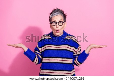 Photo portrait of lovely senior lady hold shocked empty space wear trendy blue striped garment isolated on pink color background