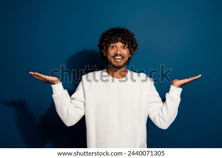 Photo of positive good mood man wear white sweater comparing arms empty space isolated dark blue color background