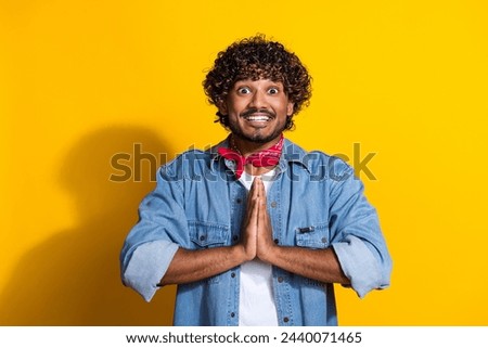 Photo portrait of attractive young man pray hands gesture wear trendy denim clothes red scarf isolated on yellow color background