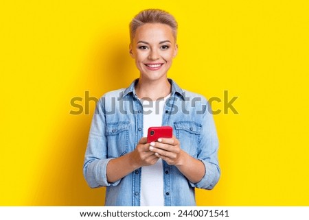 Photo portrait of lovely young lady hold telephone influencer wear trendy jeans garment isolated on yellow color background