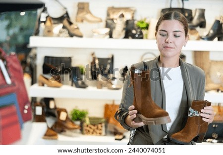 Young woman buying ankle boots in shoe store..