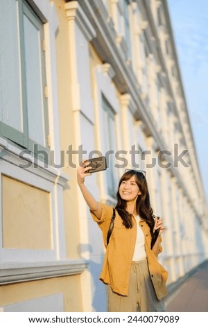 Traveler asian woman 30s making a livestream and sefie with a smartphone enjoying travel in Bangkok, Thailand. Journey trip lifestyle, world travel explorer or Asia summer tourism concept.
