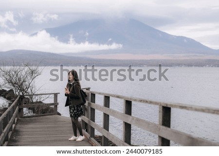Woman captures the breathtaking scenery of Mount Fuji, a symbol of Japan's natural beauty. A peaceful and calm moment amid the tranquil waters of lake.