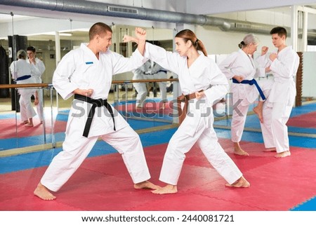 Determined young girl wearing kimono practicing martial arts techniques paired with experienced trainer in training room