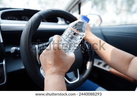 Asian woman driver hold drink in car, dangerous and risk an accident.