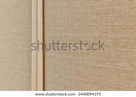 the side of a wall that has been made out of wood and is covered with light brown fabric, it's close up