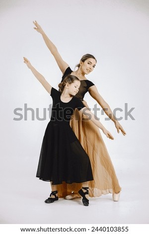 Mother and daughter ballet dancers against white background
