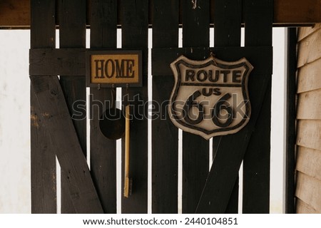 Vintage Route 66 Road Sign and Distressed Home Sign Hanging on Weathered Wooden Fence Royalty-Free Stock Photo #2440104851
