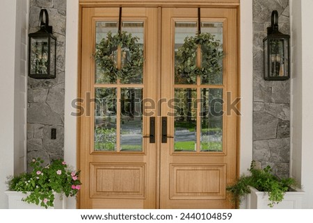 Countryside Cobblestone Cottage Grand Double Front Wood Entry Doors with Glass Panes, Decorative Sidelights, Exterior Lanterns, and Lush Greenery Royalty-Free Stock Photo #2440104859