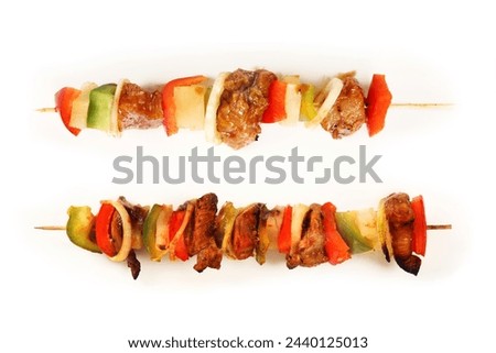 A picture of two shashlicks one grilled and one raw over white background