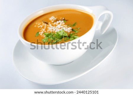 A picture of a modern bowl of tomato soup with noodle and parsley over white background