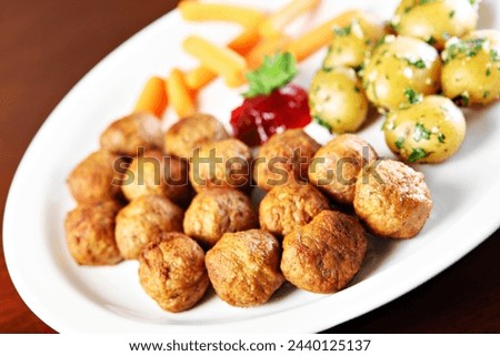 A picture of traditional swedish meatballs served with potatoes and baby carrots