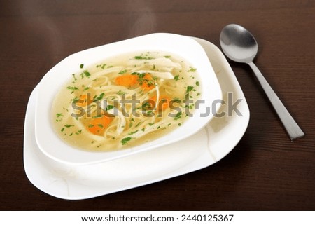 A picture of a bowl of traditional Polish chicken soup served in a bowl over wooden background