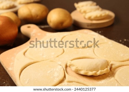 A picture of traditional Polish dumplings beeing prepared on the wooden surface