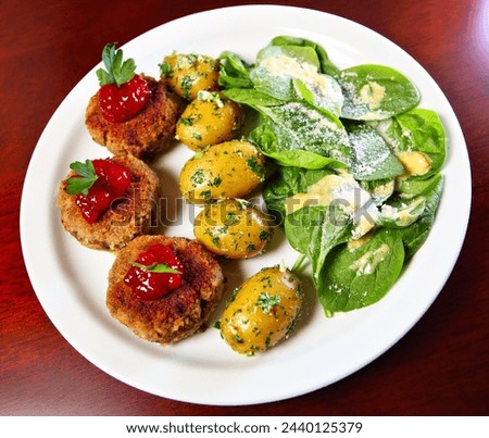 A picture of traditional Polish meatballs served with spring potatoes and spinach