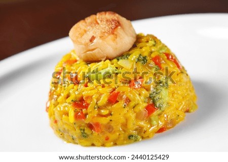 A picture of a fresh portion of paella with scallops served on a white plate