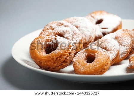 A picture of fresh home-made doughnuts with powdered sugar on a white plate