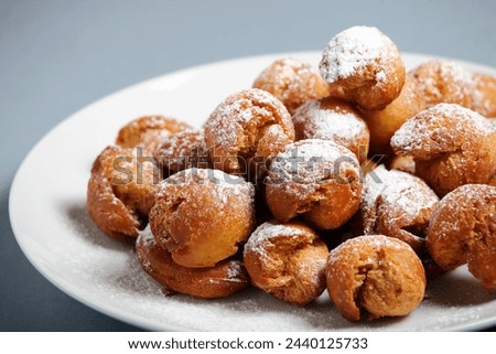 A picture of fresh home-made ball doughnuts with powdered sugar on a white plate