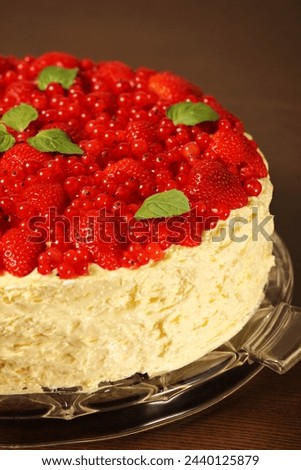 A picture of meringue cake decorated with fresh strawberries redcurrant and mint leaves