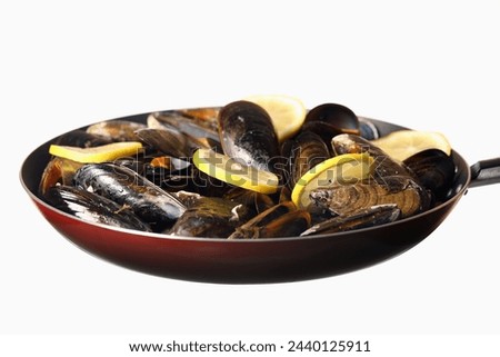 A picture of a frying pan with mussels and lemon against white background