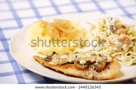 A picture of hake fish baked with mushrooms served with potatoes and salad