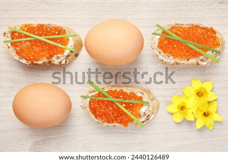 A picture of an Easter composition of eggs caviar and flowers over natural background