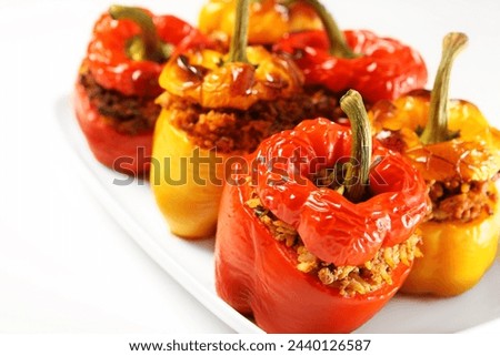 A picture of red and yellow stuffed peppers baked and served on a white plate