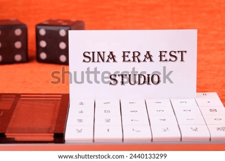 Sina era est studio It means Without anger and addiction on a white business card on a calculator on an orange background