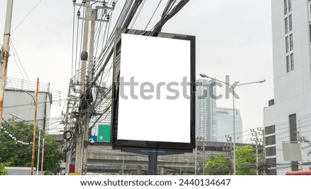An image of a billboard on a vertical black LED screen in a city. which is just below the level of the wires. There is a high-voltage electric pole located not far away.