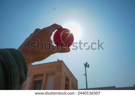 A picture of a cricket ball holding by a person facing the sun 