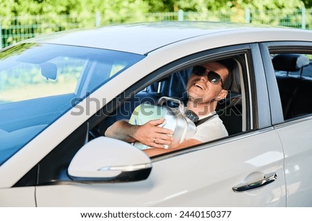 Happy man hugging canister full of gasoline. Man glad that took canister and have extra fuel for unforeseen circumstances. Smiling man in sunglasses sitting in white car and holding cistern. Royalty-Free Stock Photo #2440150377