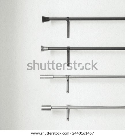 Minimalist Curtain Rods Display, a Set in Contrasting Colors, Upper in Matte Black Finish with Classic End Caps, with Modern Cylinder Finials, Mounted on a Clean White Wall with Sleek Metal Brackets. Royalty-Free Stock Photo #2440161457