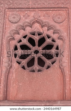 Window built of red sandstone with intricate and beautiful delicate lattice work. Perforated stone or lattice screen known as Jaali or Jali. Geometric pattern background