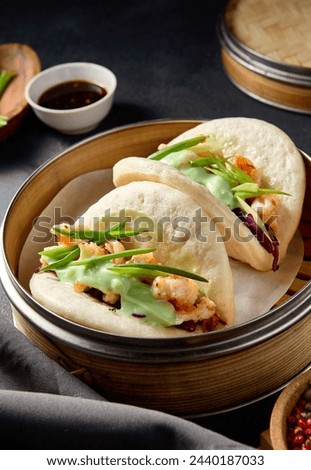 Steamed Bao buns filled with shrimp, purple cabbage, and wasabi, served on a dark table setting.