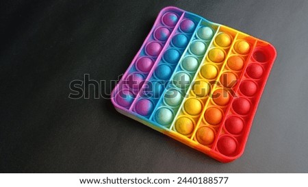 Poppit toy on black background, close-up. Colorful poppit it game Royalty-Free Stock Photo #2440188577