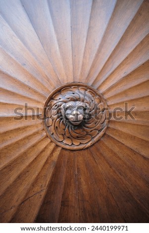 A brown wooden door with a lion head carving, adding a touch of elegance to the buildings hardwood flooring. The intricate pattern and symmetry of the design complement the stairs