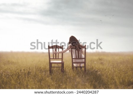 sad woman looks nostalgically at her lover's empty chair  in the middle of nature Royalty-Free Stock Photo #2440204287