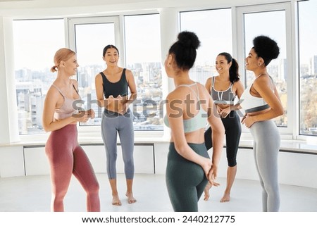 group of five happy multicultural women standing in sportwear and chatting before pilates class Royalty-Free Stock Photo #2440212775