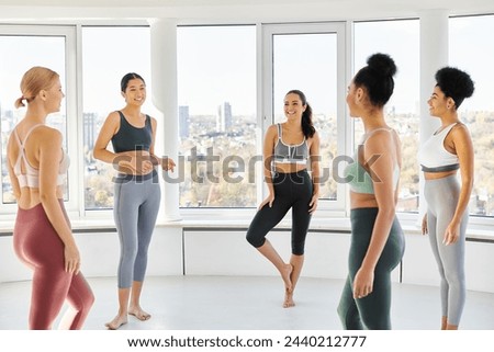group of five happy interracial women standing in sportwear and chatting before pilates class Royalty-Free Stock Photo #2440212777