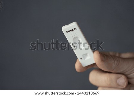 A close-up of hand holding positive streptococcus test during infection, diagnostic test done at home for telephone consultation with doctor Royalty-Free Stock Photo #2440213669
