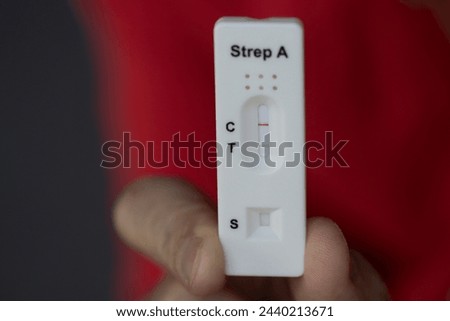 A close-up of hand holding positive streptococcus test during infection, diagnostic test done at home for telephone consultation with doctor Royalty-Free Stock Photo #2440213671
