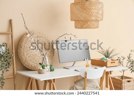 Workplace with computer and Easter decor near beige wall in office
