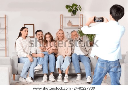 Little boy with mobile phone taking picture of his big family a home